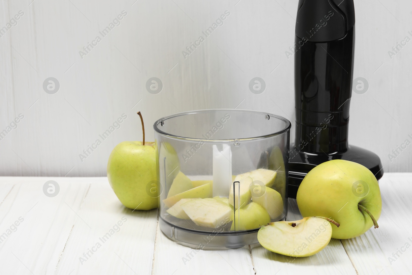 Photo of Hand blender kit and fresh apples on white wooden table, space for text