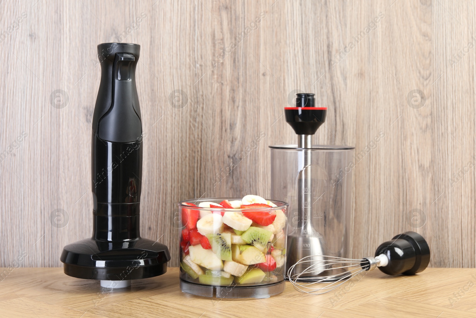 Photo of Hand blender kit with fresh fruits and strawberries on wooden table