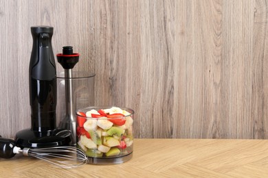 Photo of Hand blender kit with fresh fruits and strawberries on wooden table, space for text