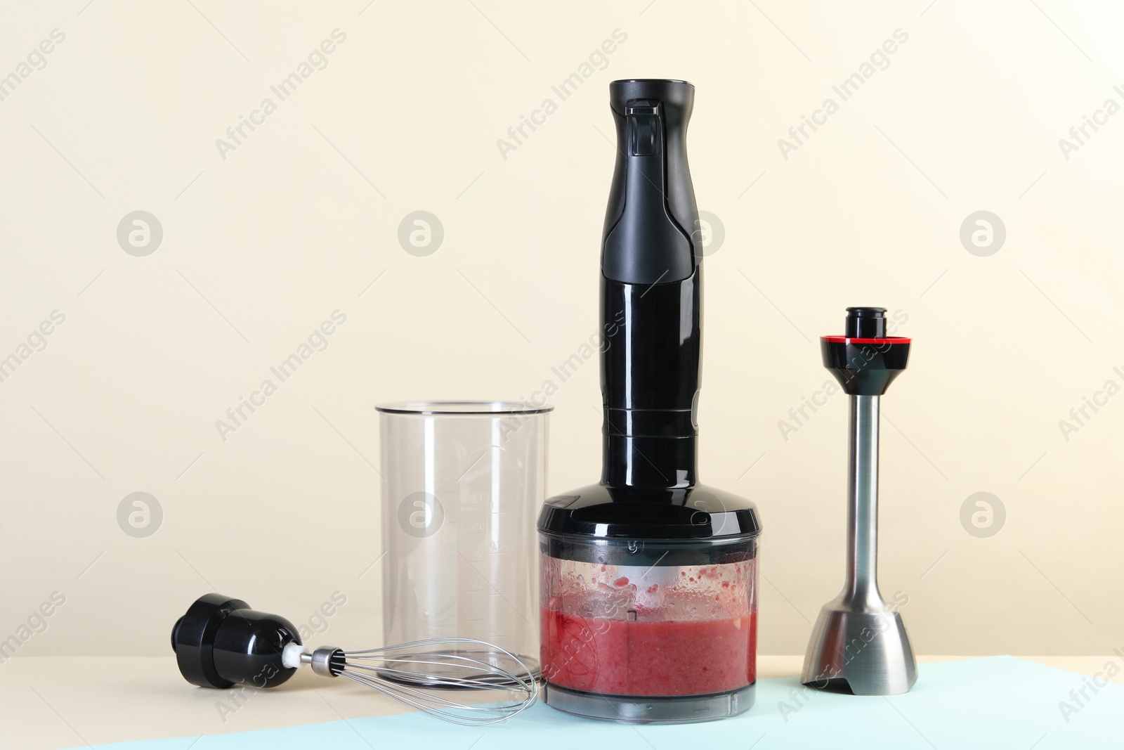 Photo of Hand blender kit and mixture of ingredients on color background