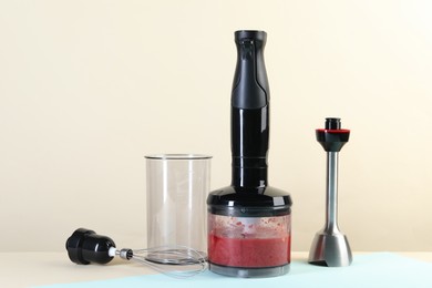 Hand blender kit and mixture of ingredients on color background