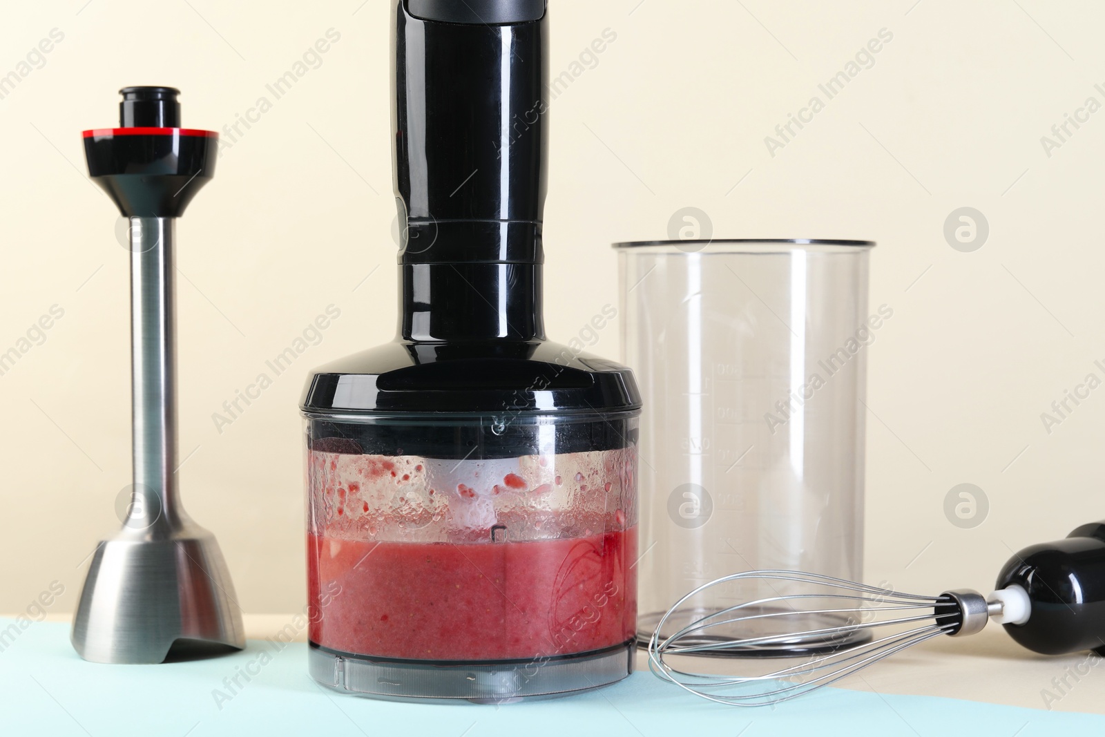 Photo of Hand blender kit and mixture of ingredients on color background