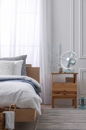 Photo of Stylish living room interior with bed, bedside table and fan