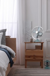 Photo of Stylish living room interior with bed, bedside table and fan