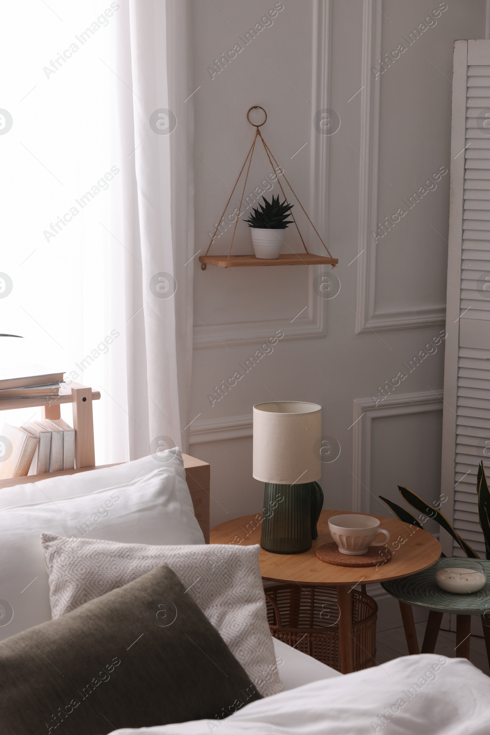 Photo of Stylish living room interior with bed, bedside tables, lamp and houseplants