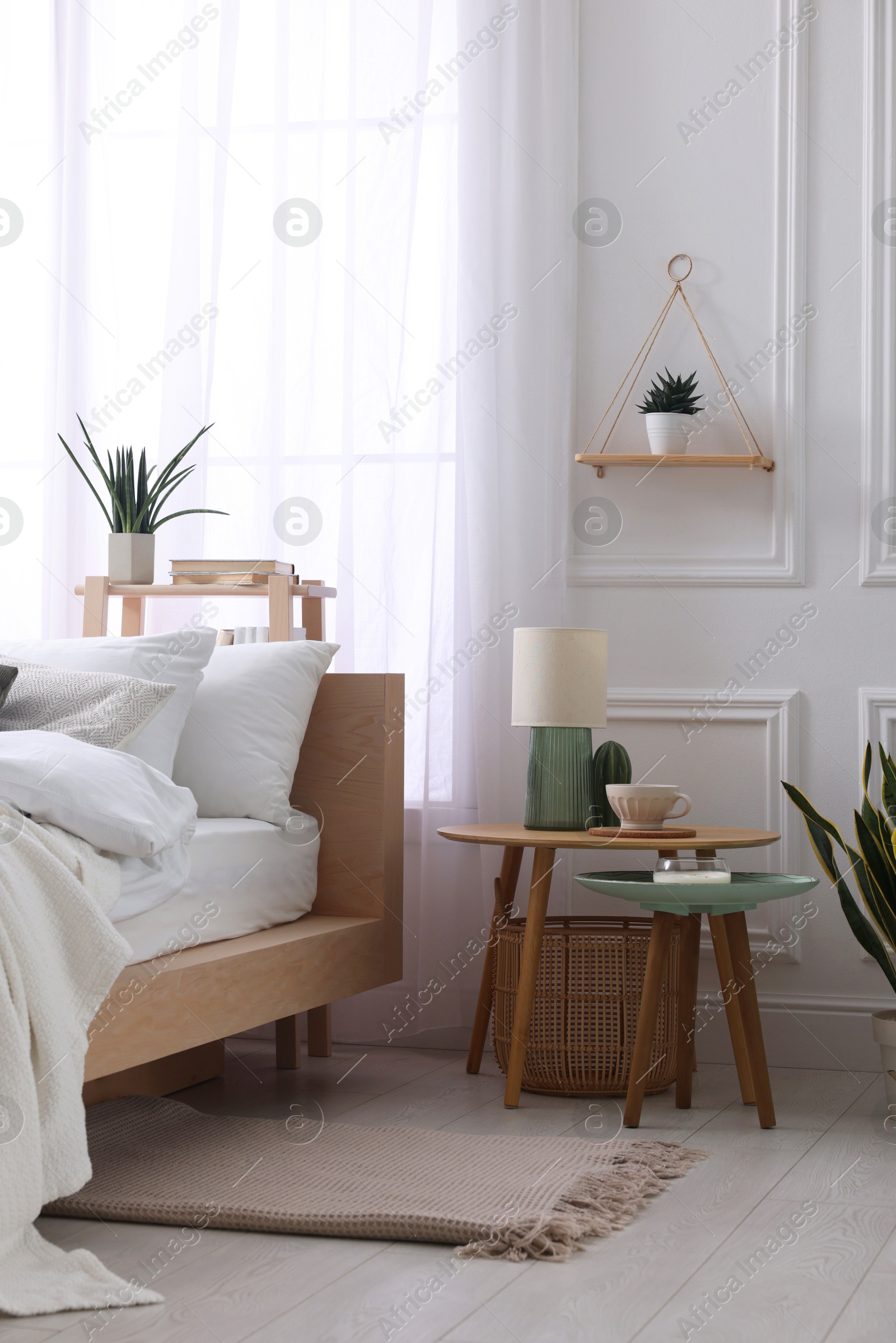 Photo of Stylish living room interior with bed, bedside tables, lamp and houseplants