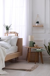 Stylish living room interior with bed, bedside tables, lamp and houseplants