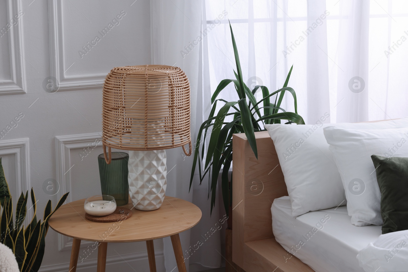 Photo of Stylish living room interior with bed, bedside table, lamp and houseplants