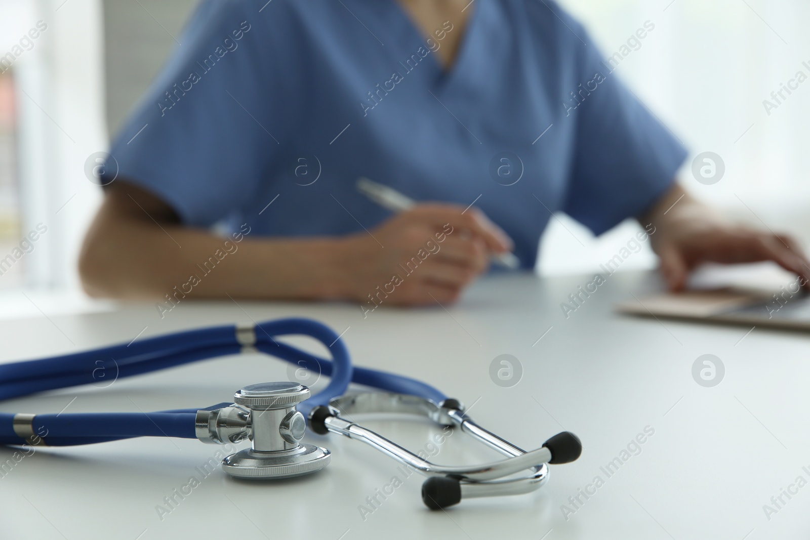 Photo of Doctor at white table in hospital, focus on medical stethoscope