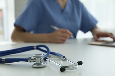 Doctor at white table in hospital, focus on medical stethoscope