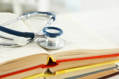 Photo of One new medical stethoscope and books on table, closeup