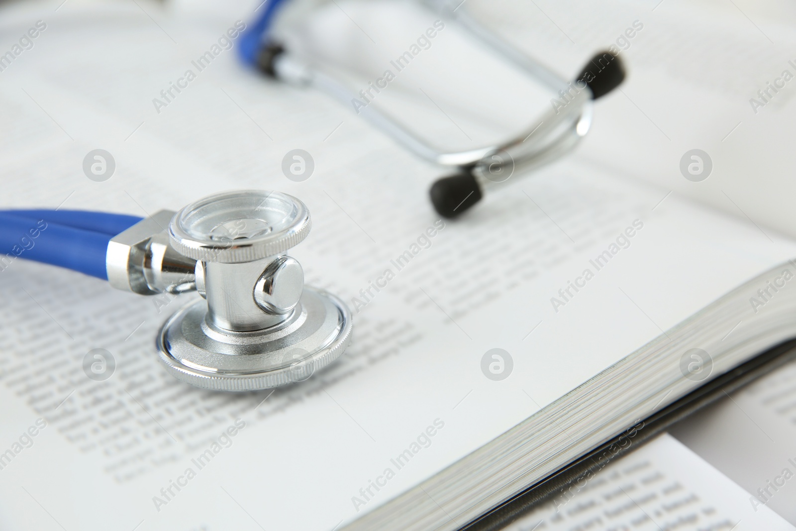 Photo of One medical stethoscope and books on table, closeup