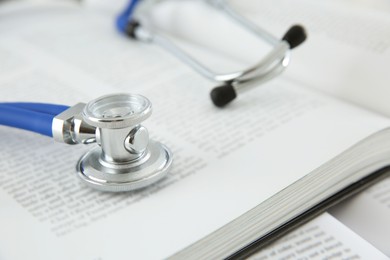 One medical stethoscope and books on table, closeup