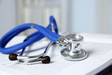 Photo of One medical stethoscope and book on table, closeup