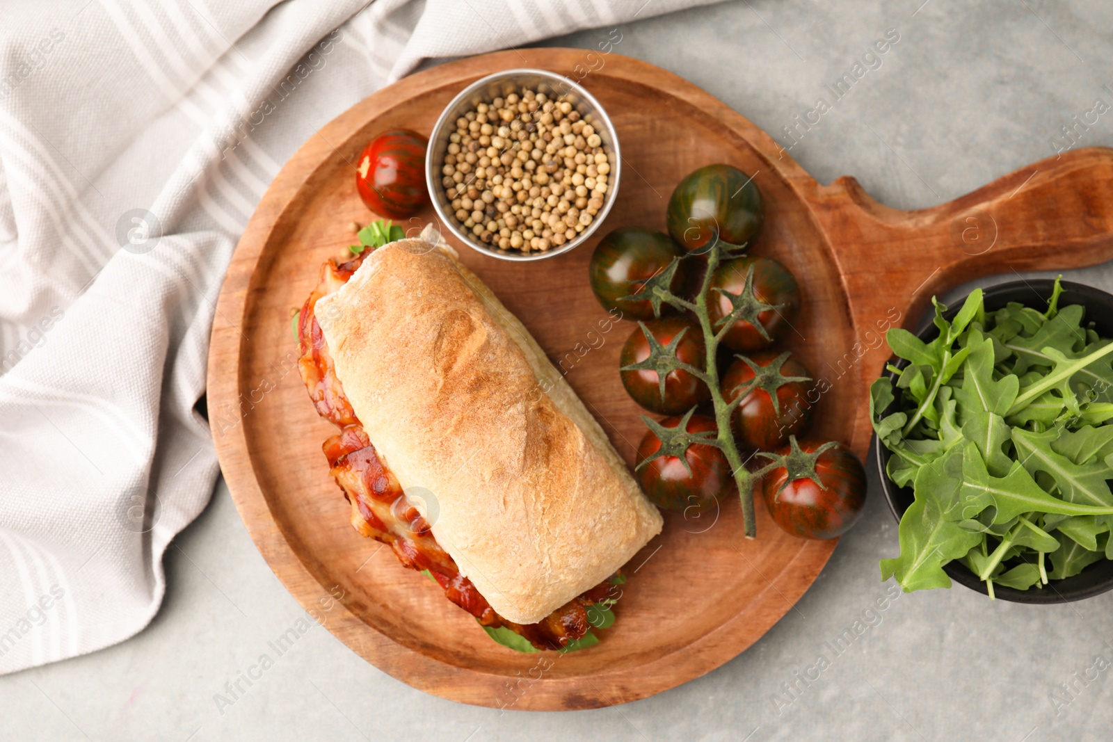 Photo of Tasty sandwich with bacon, tomatoes and spices on grey table, flat lay