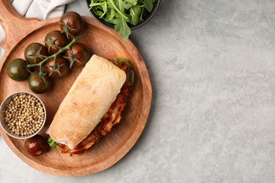 Photo of Tasty sandwich with bacon, tomatoes and spices on grey table, flat lay. Space for text