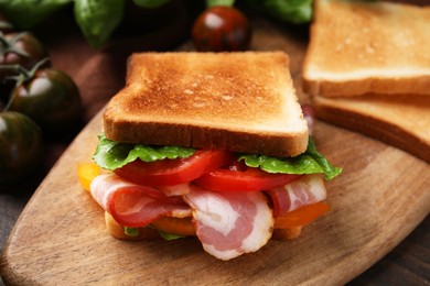 Photo of Tasty sandwich with bacon and tomato on wooden table, closeup