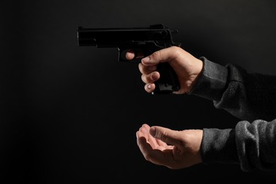 Photo of Dangerous criminal with gun on black background, closeup. Armed robbery