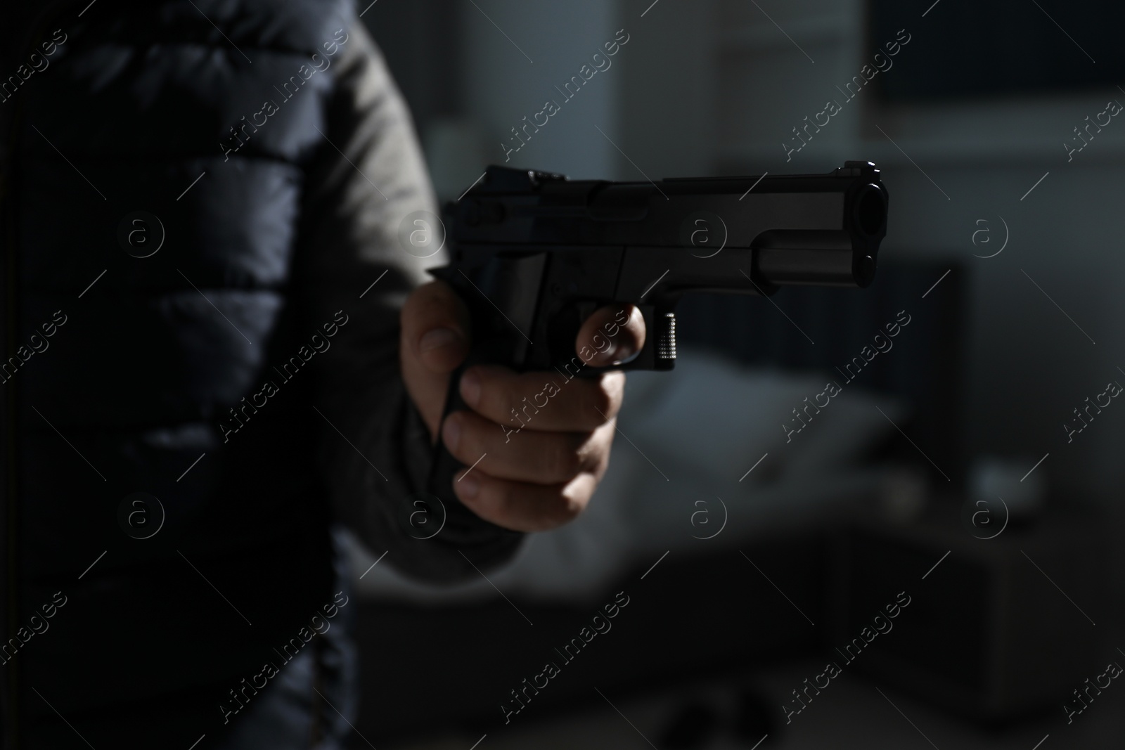 Photo of Dangerous criminal with gun in foreign house, closeup. Armed robbery