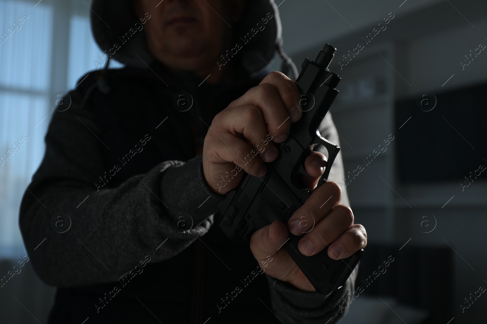 Photo of Dangerous criminal with gun in foreign house, closeup. Armed robbery