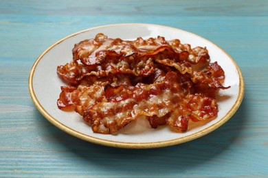 Photo of Slices of tasty fried bacon on light blue wooden table