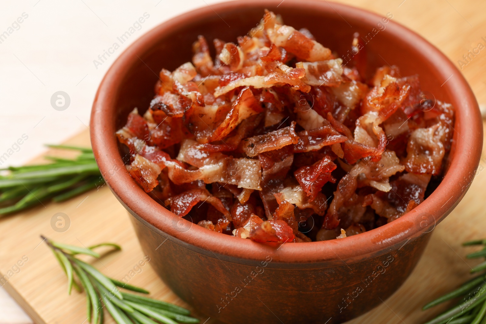 Photo of Pieces of tasty fried bacon in bowl on table, closeup