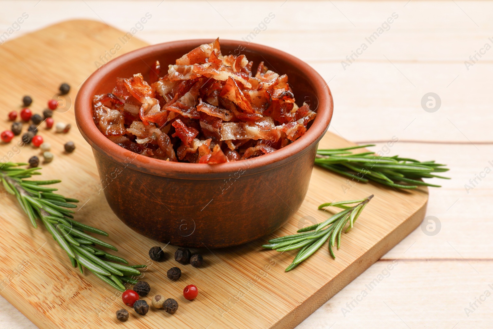 Photo of Pieces of tasty fried bacon in bowl and spices on wooden table, closeup