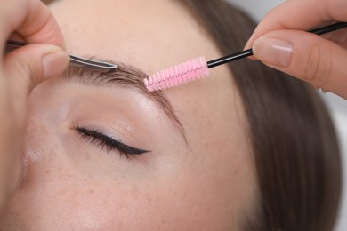 Photo of Beautician making eyebrow correction to young woman, closeup