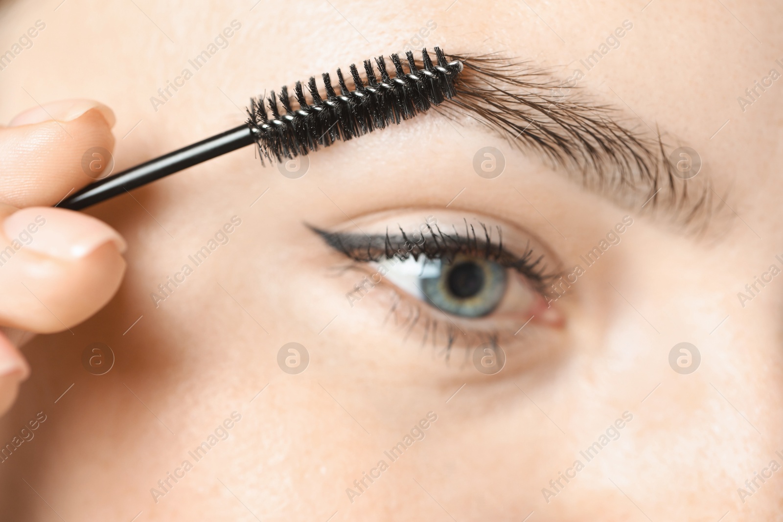 Photo of Young woman with spoolie brush, closeup. Eyebrow correction