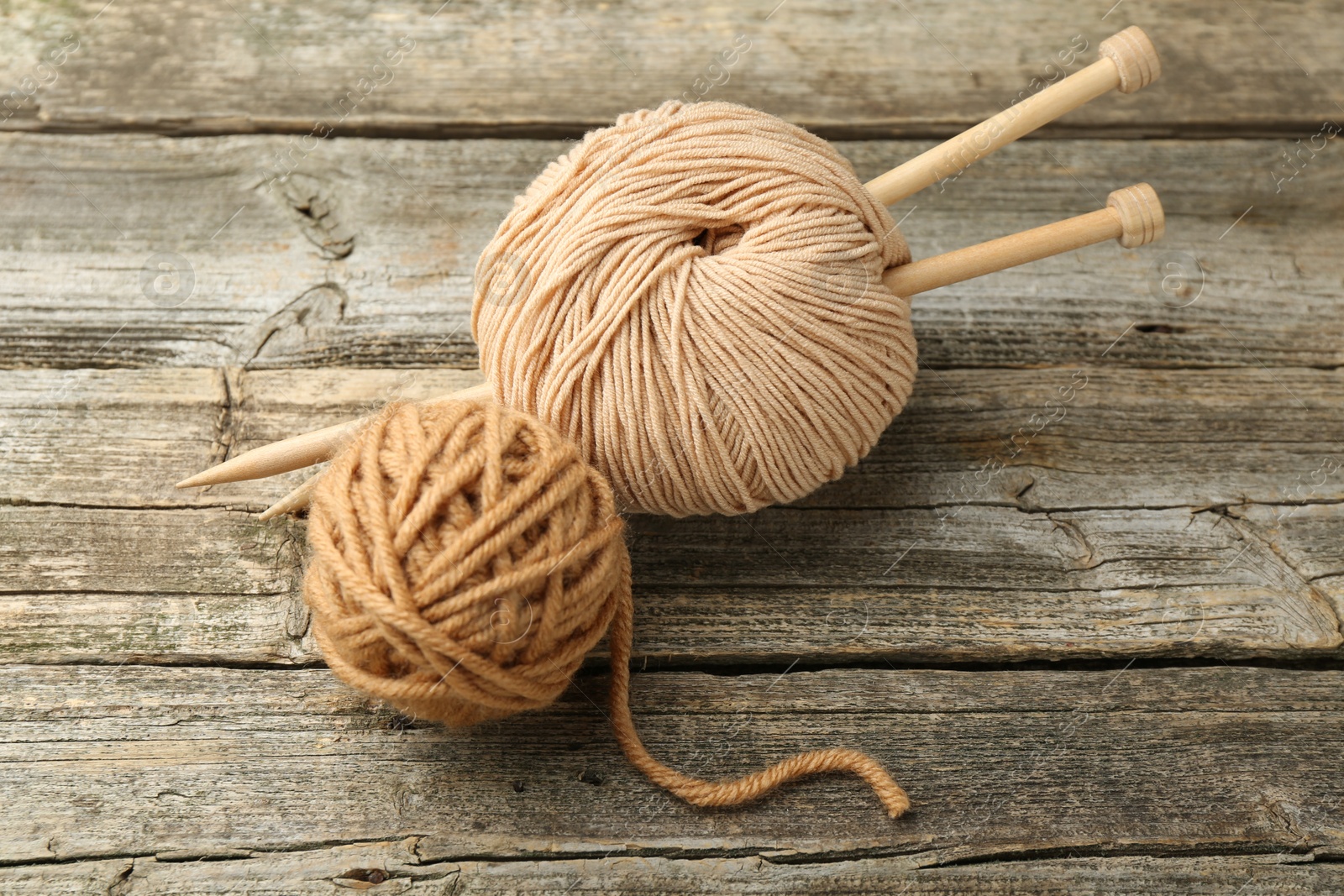 Photo of Skeins of soft yarn and knitting needles on wooden table