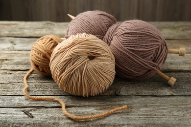 Skeins of soft yarn and knitting needles on wooden table