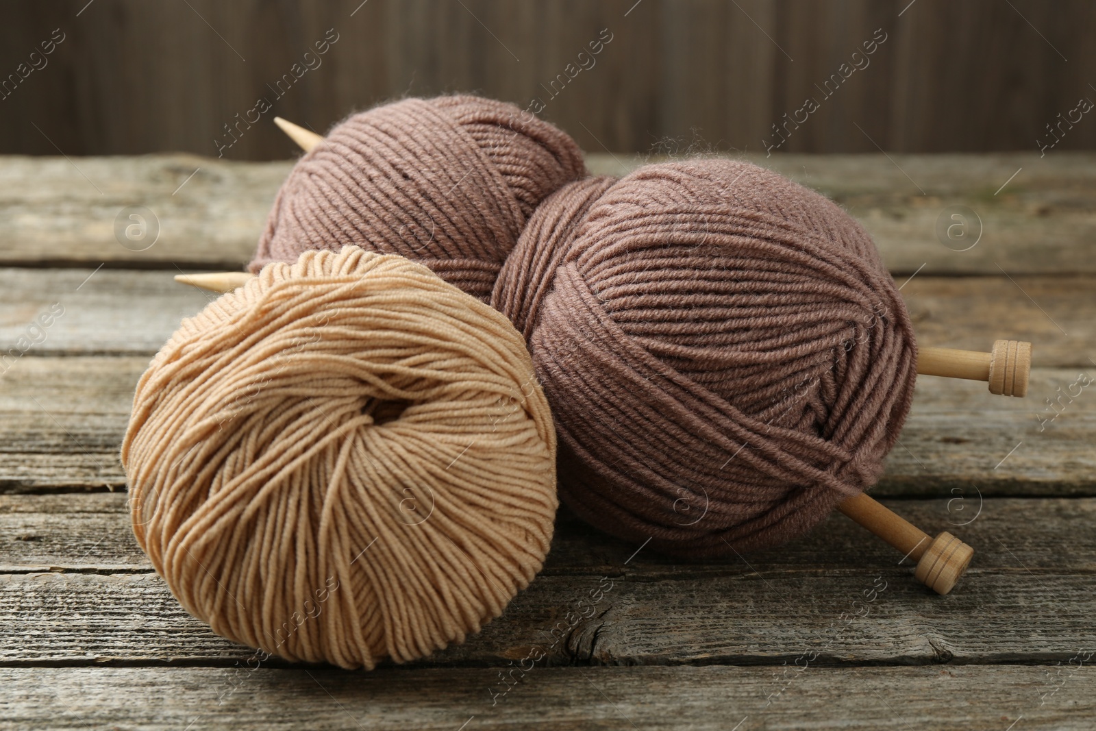 Photo of Skeins of soft yarn and knitting needles on wooden table