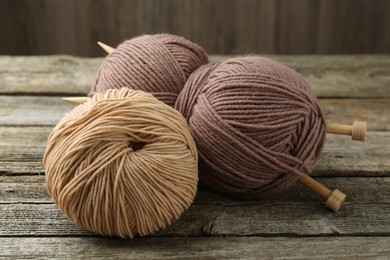 Skeins of soft yarn and knitting needles on wooden table