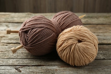 Skeins of soft yarn and knitting needles on wooden table