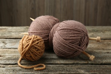 Skeins of soft yarn and knitting needles on wooden table