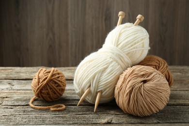 Photo of Skeins of soft yarn and knitting needles on wooden table