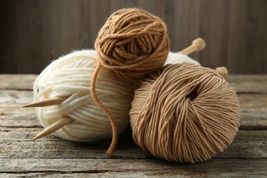 Photo of Skeins of soft yarn and knitting needles on wooden table