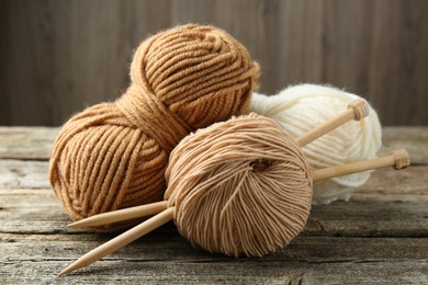 Skeins of soft yarn and knitting needles on wooden table