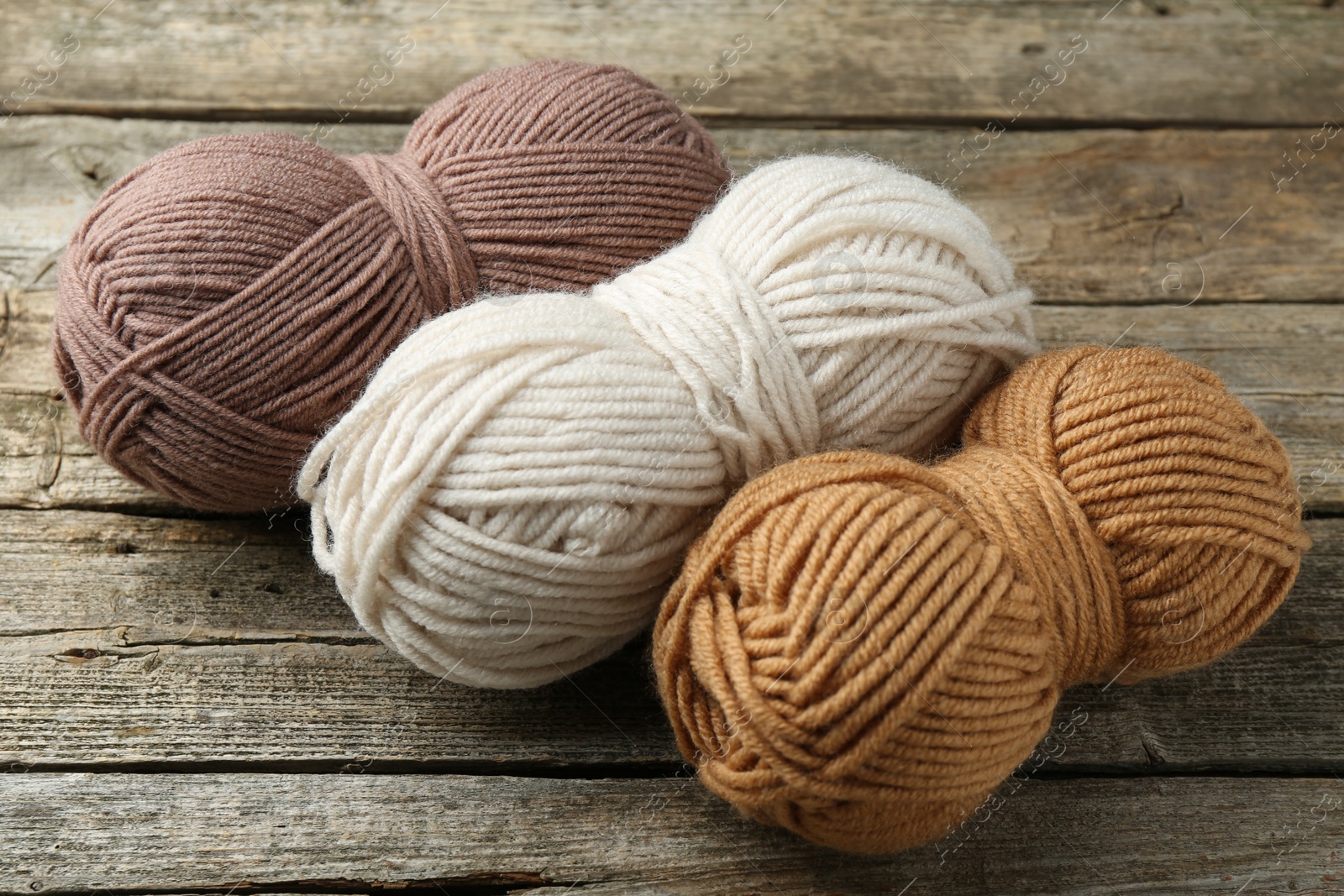 Photo of Skeins of soft yarn for knitting on wooden table