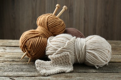 Skeins of soft yarn and knitting needles on wooden table