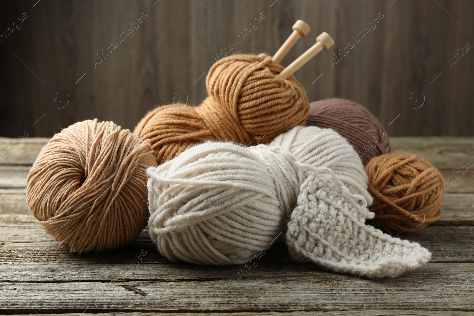 Photo of Skeins of soft yarn and knitting needles on wooden table