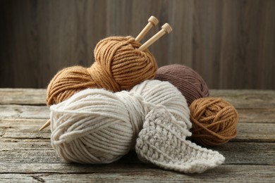 Skeins of soft yarn and knitting needles on wooden table