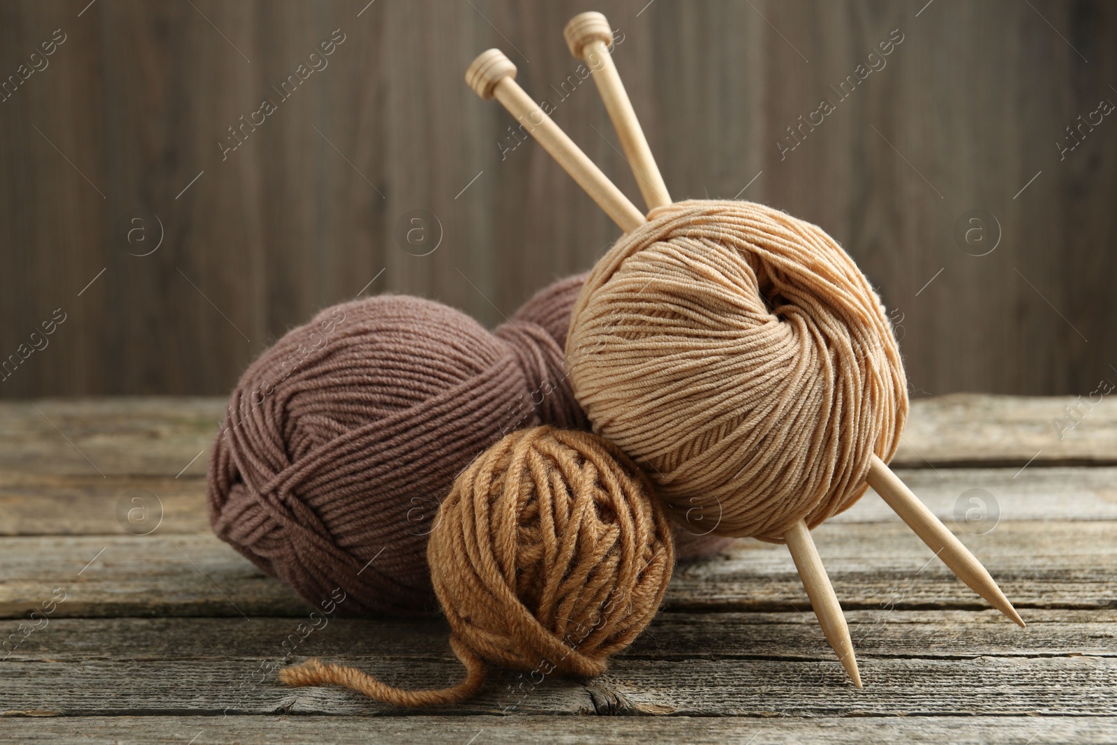 Photo of Skeins of soft yarn and knitting needles on wooden table