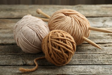 Skeins of soft yarn and knitting needles on wooden table