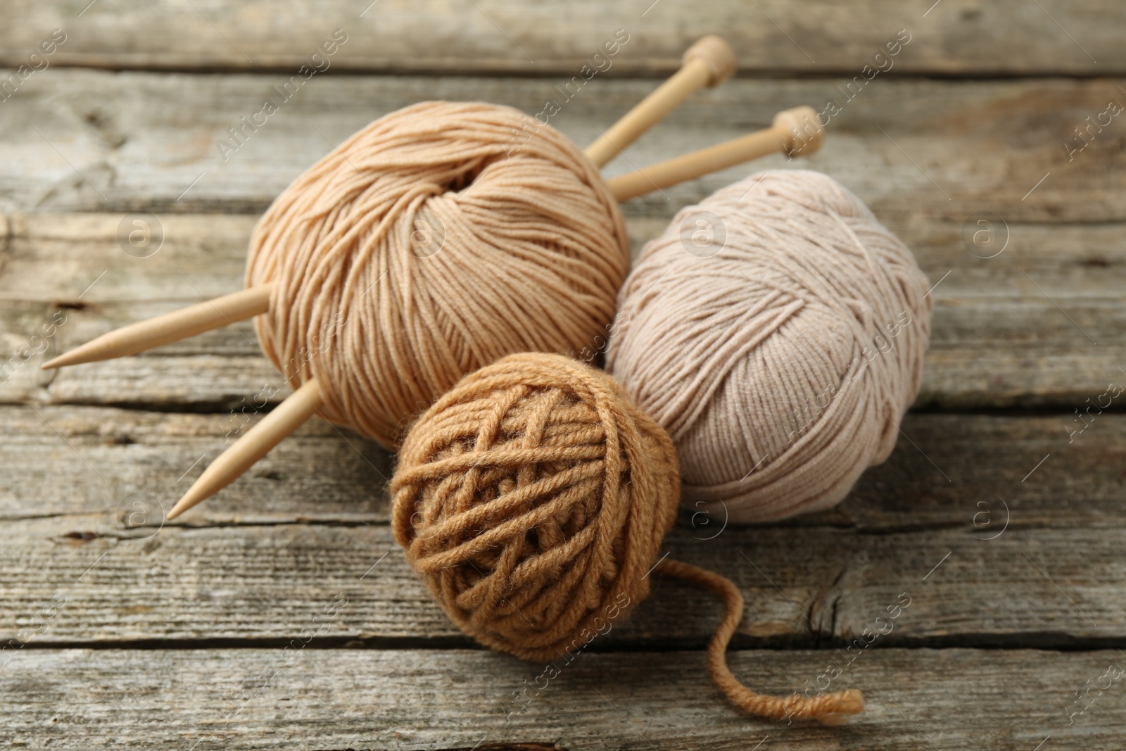 Photo of Skeins of soft yarn and knitting needles on wooden table