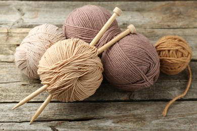 Photo of Skeins of soft yarn and knitting needles on wooden table