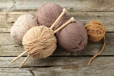 Skeins of soft yarn and knitting needles on wooden table, above view