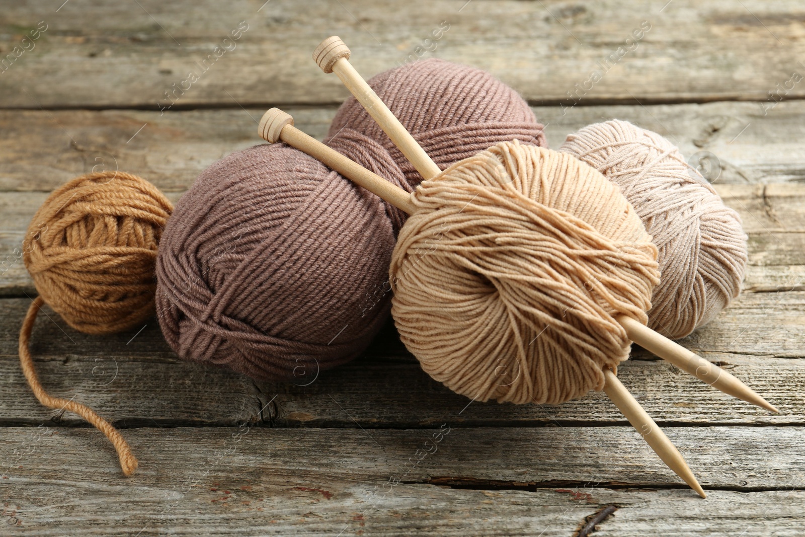 Photo of Skeins of soft yarn and knitting needles on wooden table