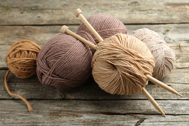 Skeins of soft yarn and knitting needles on wooden table