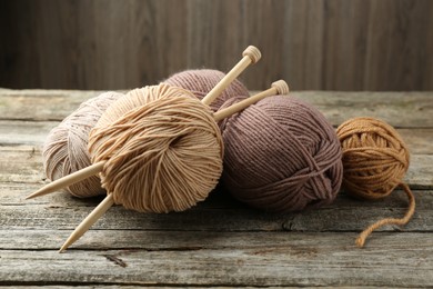 Photo of Skeins of soft yarn and knitting needles on wooden table